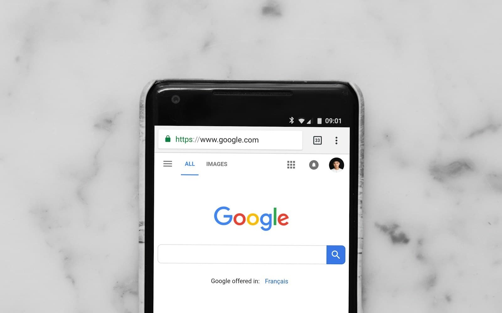 Un móvil sobre una mesa de mármol con la página de inicio de Google abierta